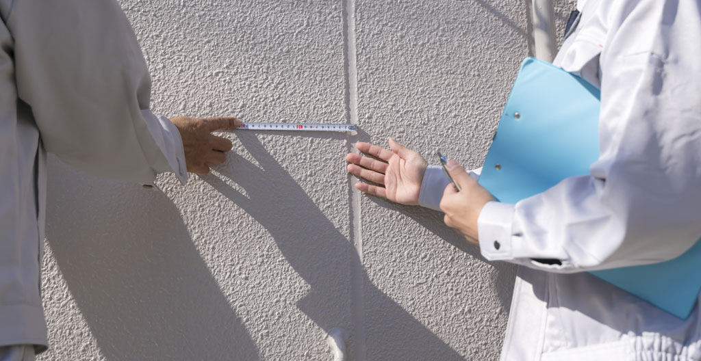 Persona midiendo el ancho de una terraza con cinta métrica para calcular las dimensiones del toldo a medida